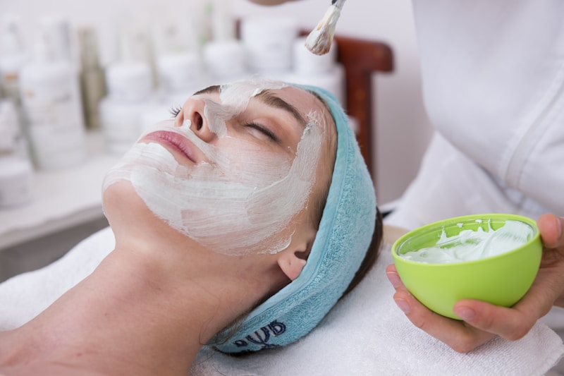 Woman lying on blue towel with white cream on face